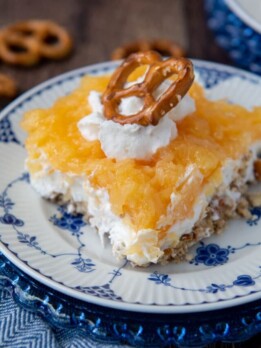close up of a slice of pretzel salad with pineapple with whipped cream and pretzel on top