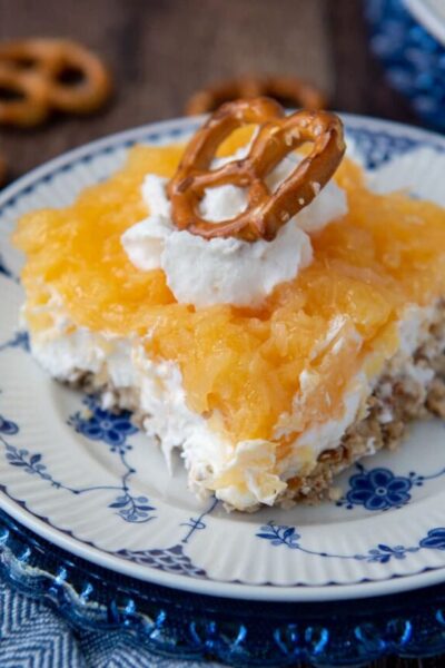close up of a slice of pretzel salad with pineapple with whipped cream and pretzel on top