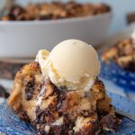 another shot of a serving of chocolate chip bread pudding on a blue plate with a scoop of melting ice cream on top