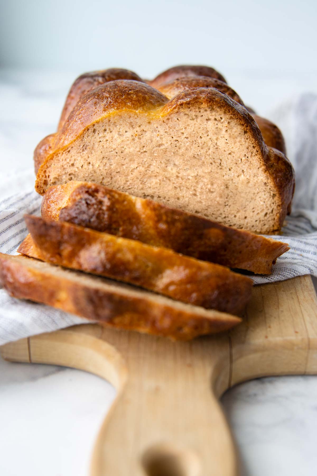 a sliced loaf of challah facing straight on with a white towel underneath.