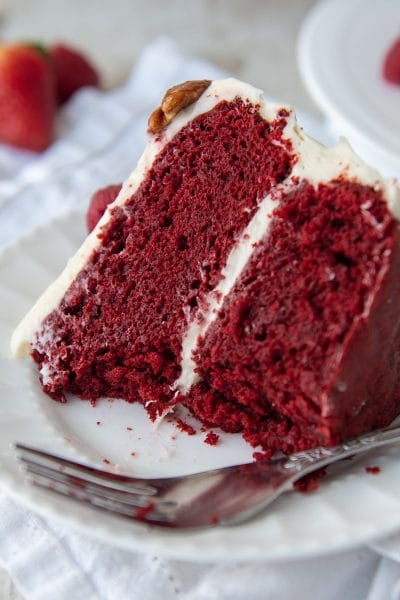 a slice of gluten free red velvet cake on a white plate with bites taken out