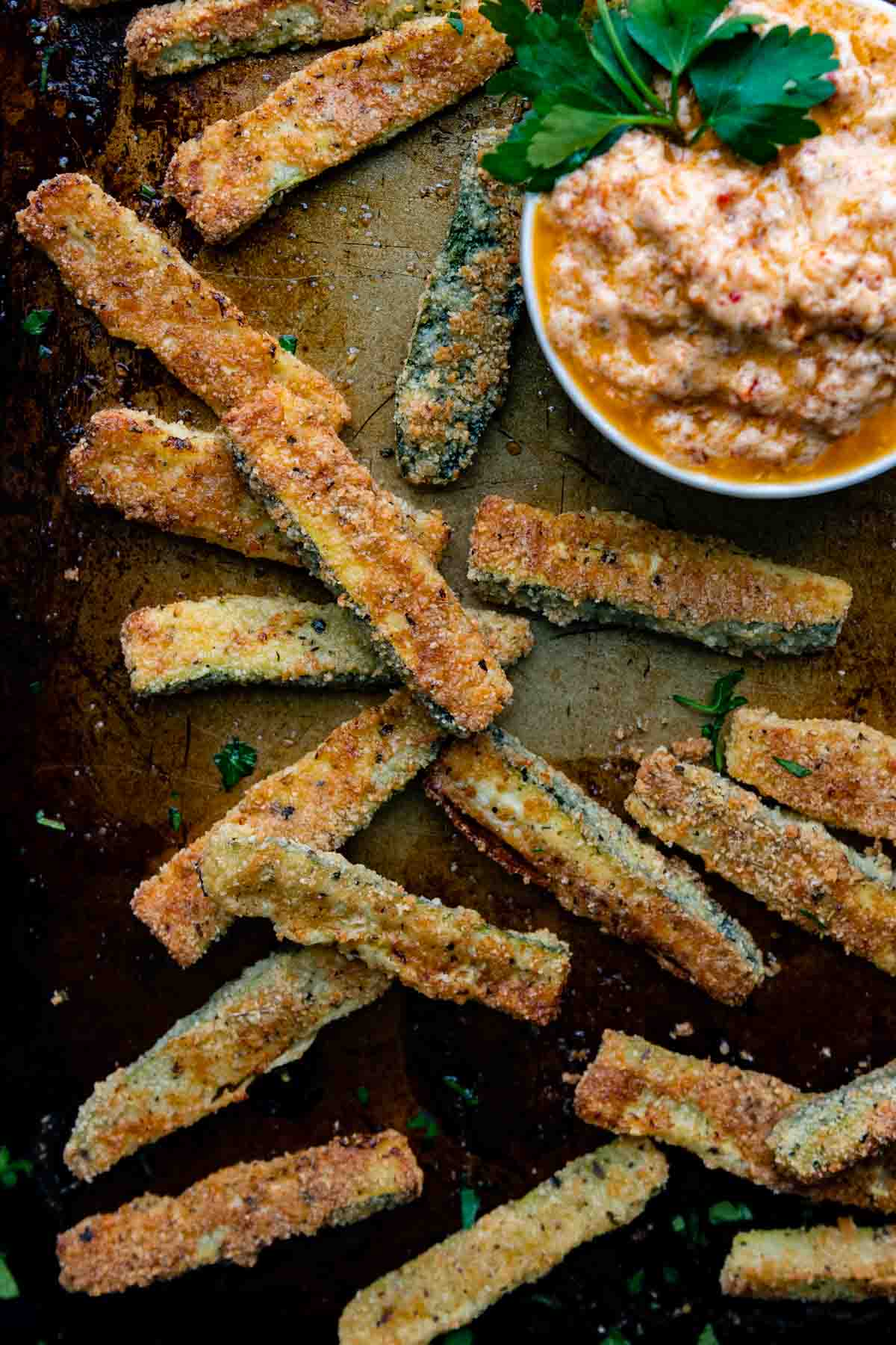 zucchini fries on a baking sheet with dipping sauce.
