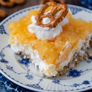 close up of a slice of pretzel salad with pineapple with whipped cream and pretzel on top