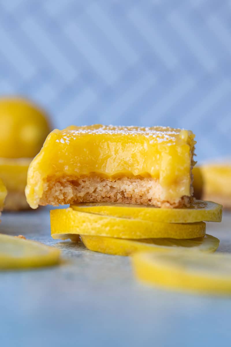 a gluten free lemon bar with a bite taken out sitting on top lemon slices