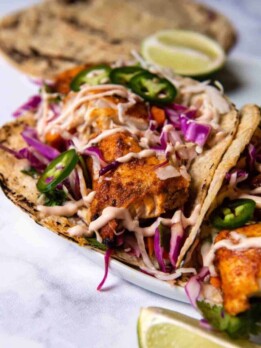 close up shot of a fish taco on a white marble top