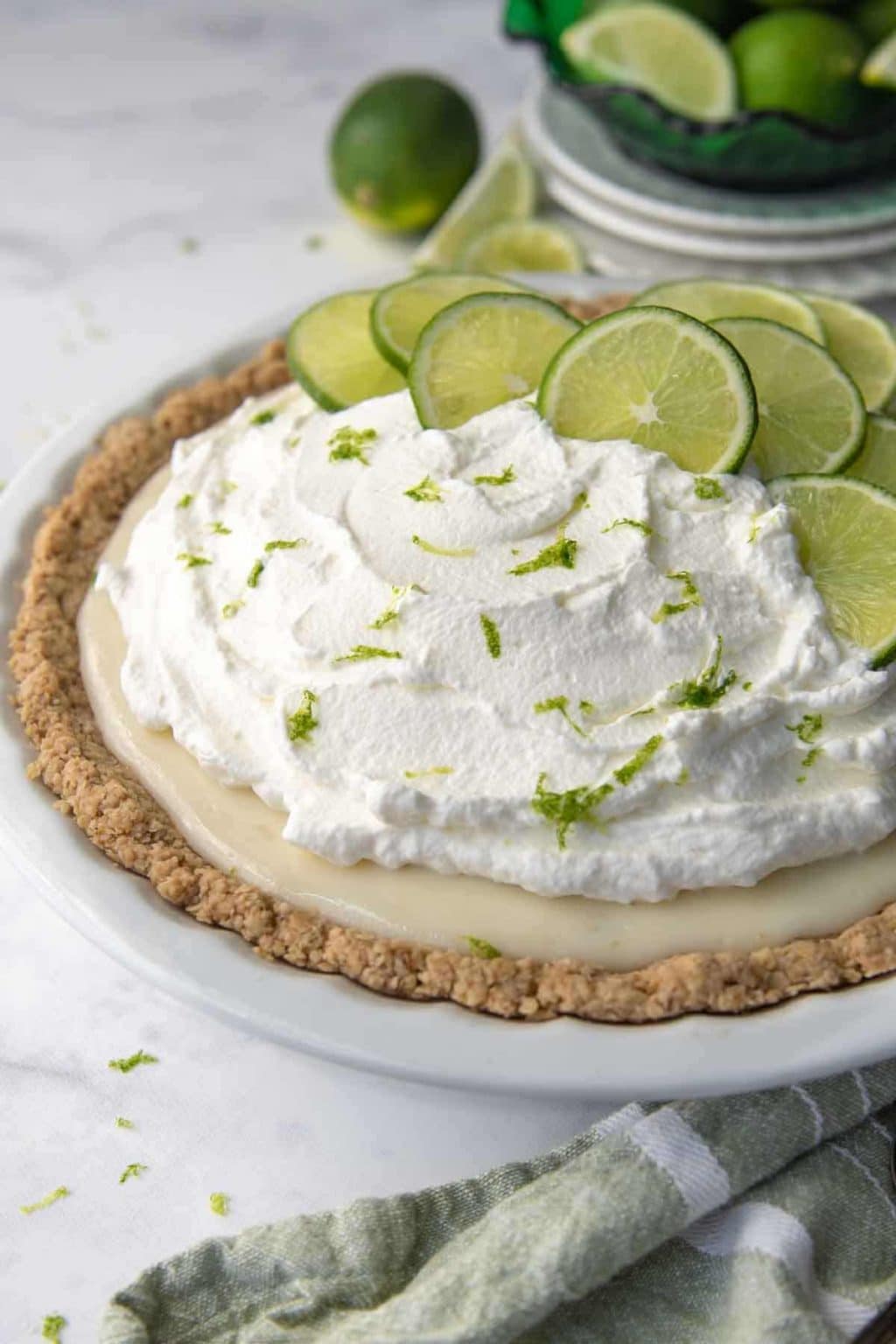 whole gluten free key lime pie in a white pie dish with sliced limes on top