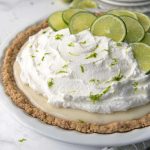 whole gluten free key lime pie in a white pie dish with sliced limes on top