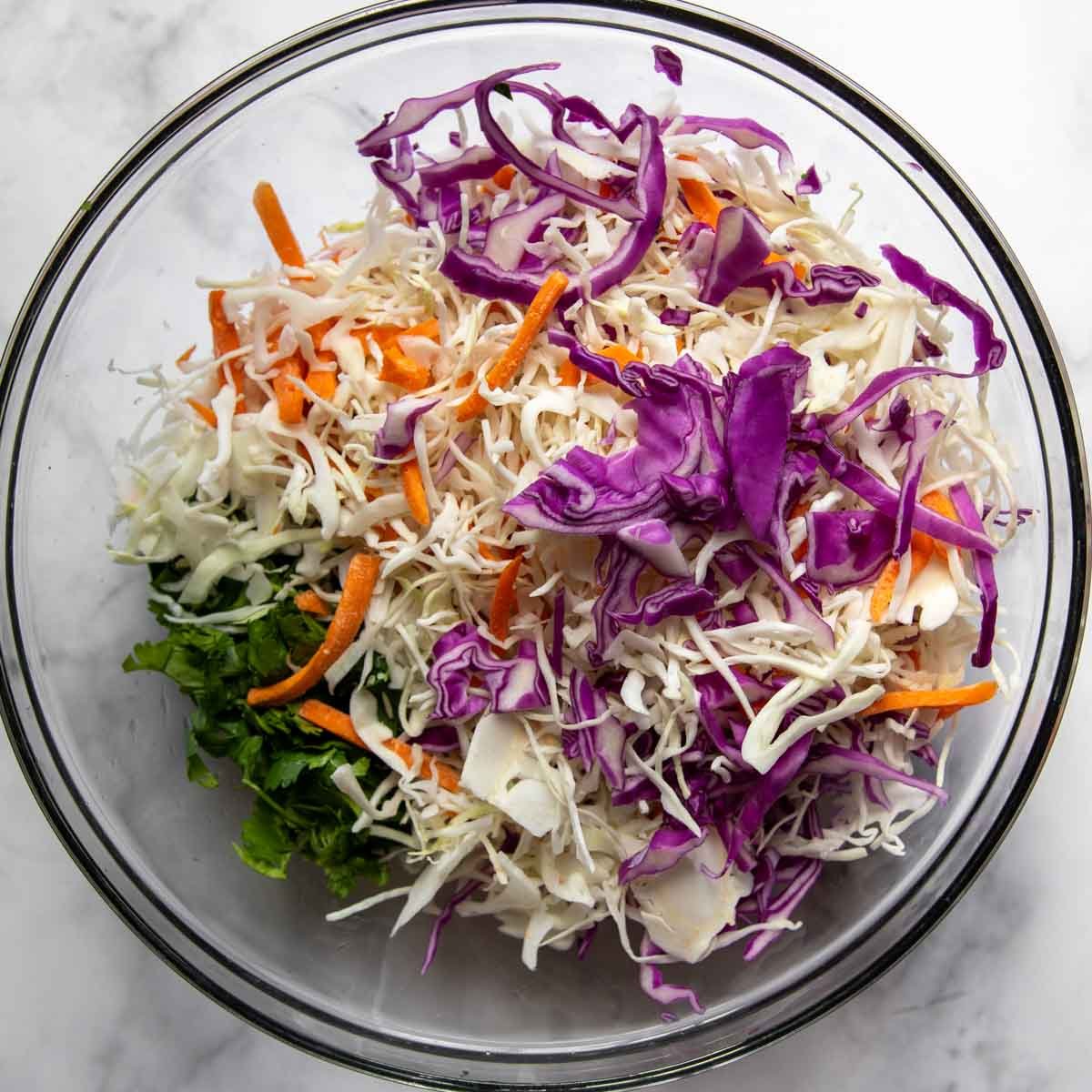 the coleslaw ingredients in a glass bowl.