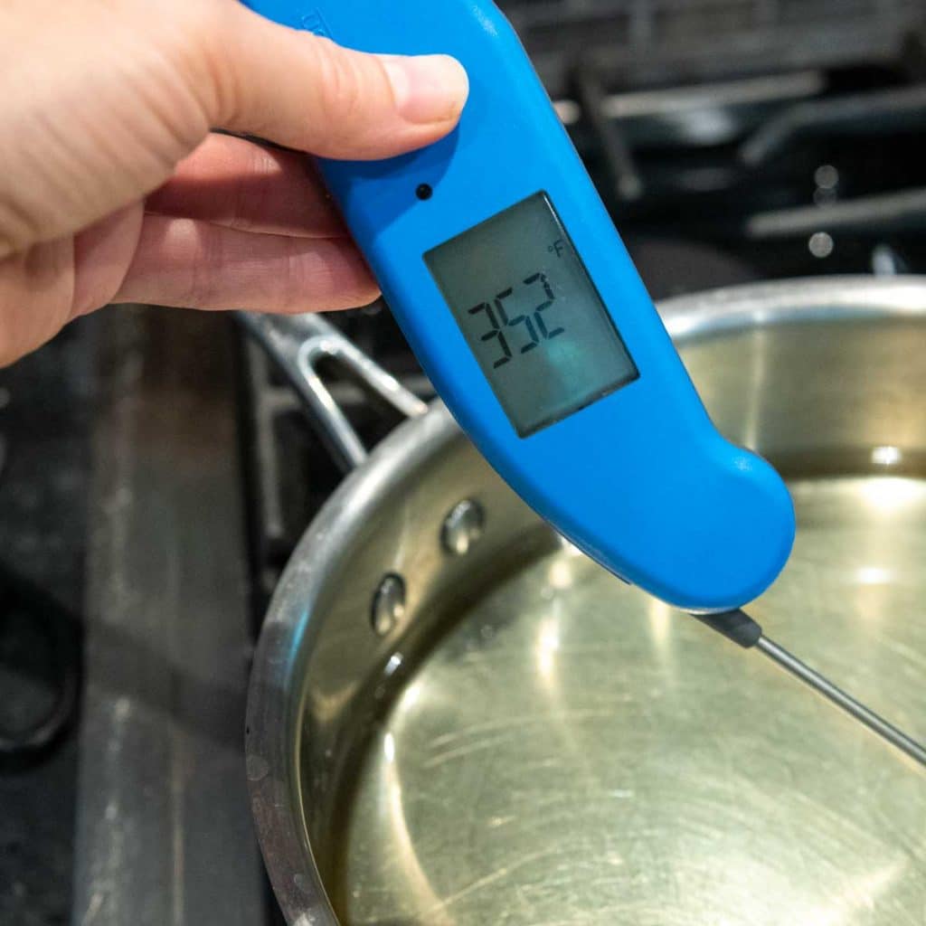 a thermometer going into cooking oil on the stove