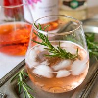 a rose spritz cocktail with bottles to make it in the background