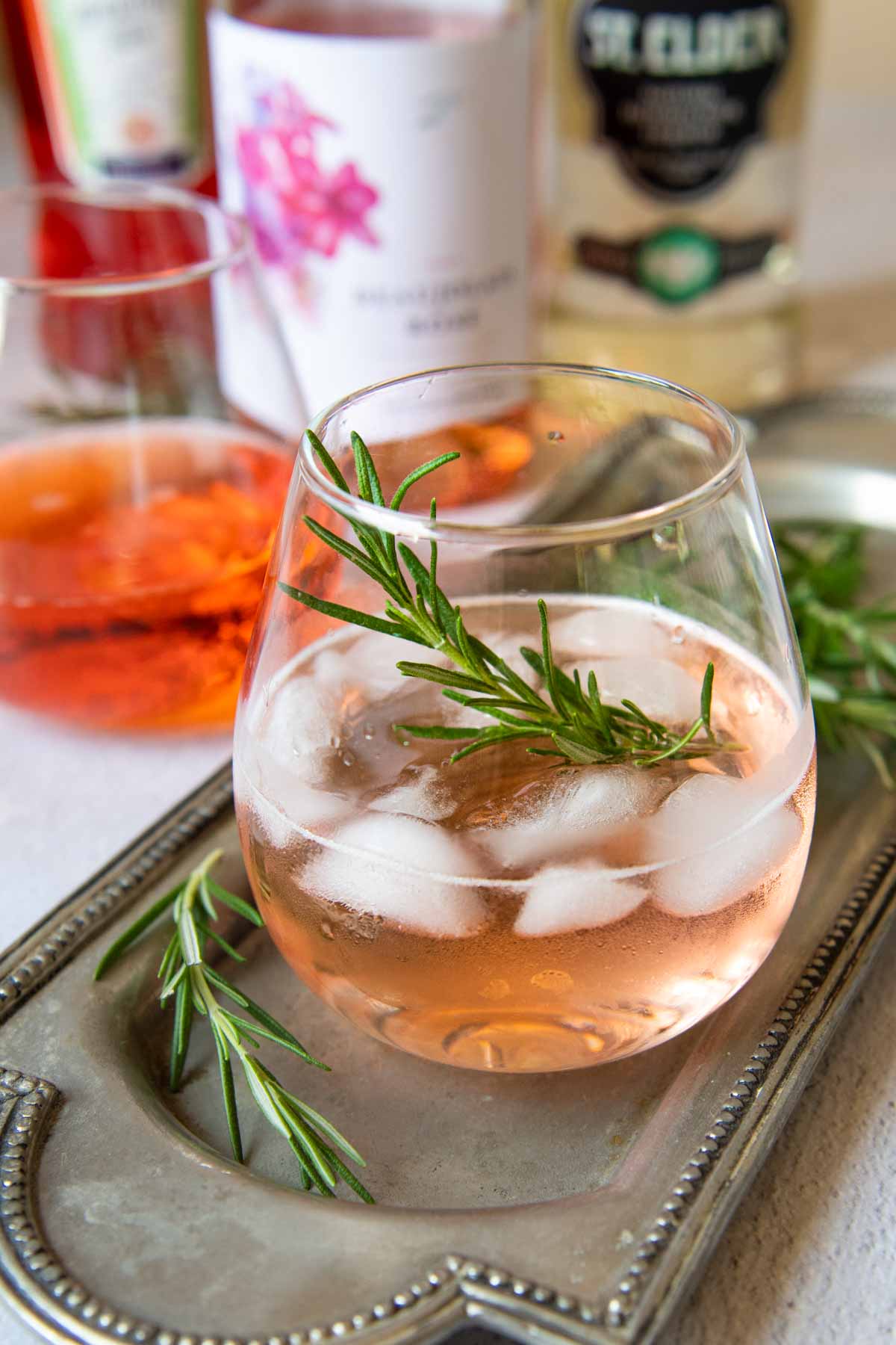 a rose spritz cocktail with bottles to make it in the background