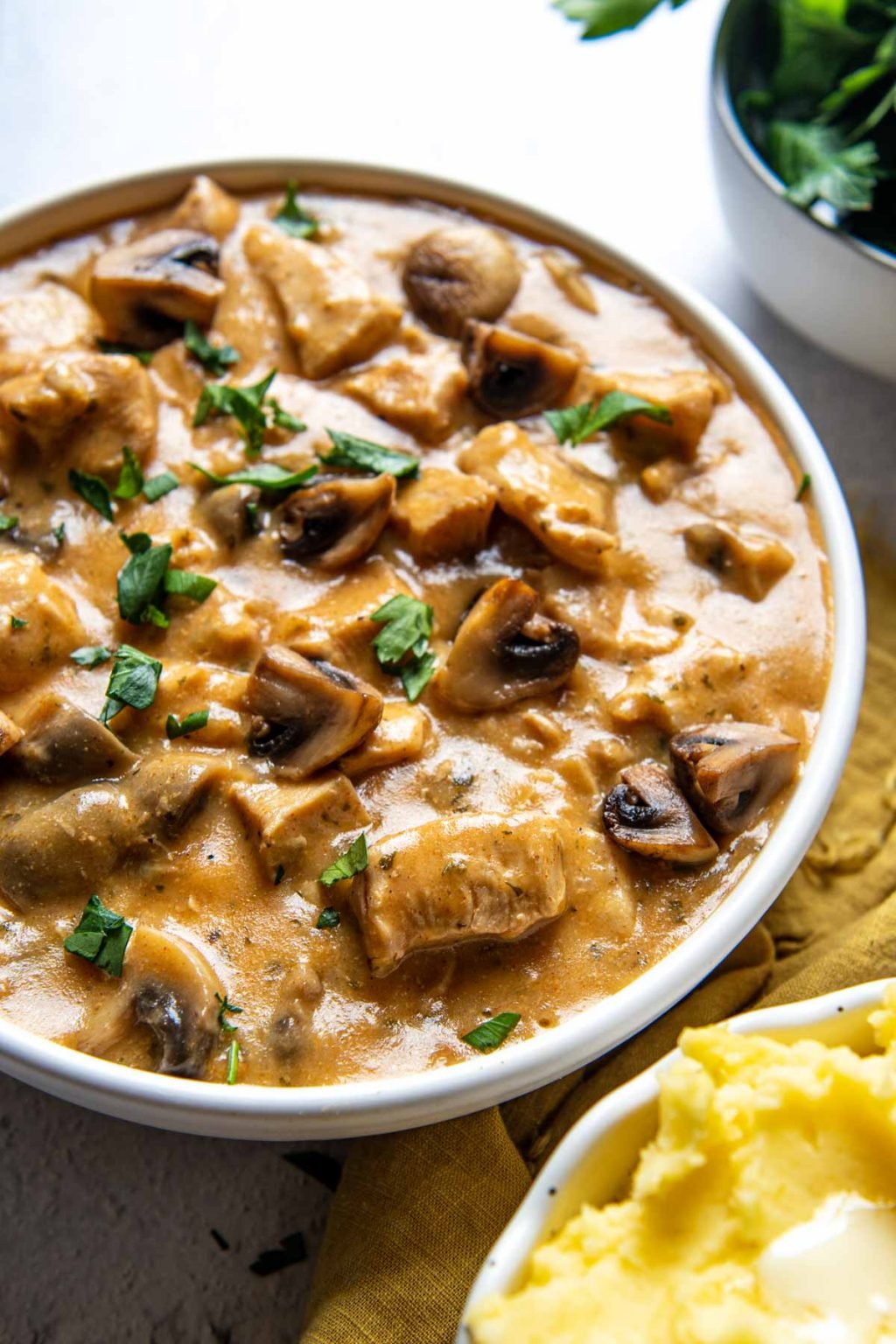 a bowl of instant pot stroganoff with a side of mashed potatoes next to it