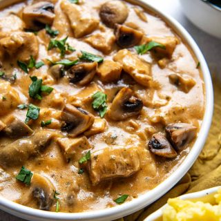 a bowl of instant pot stroganoff with a side of mashed potatoes next to it