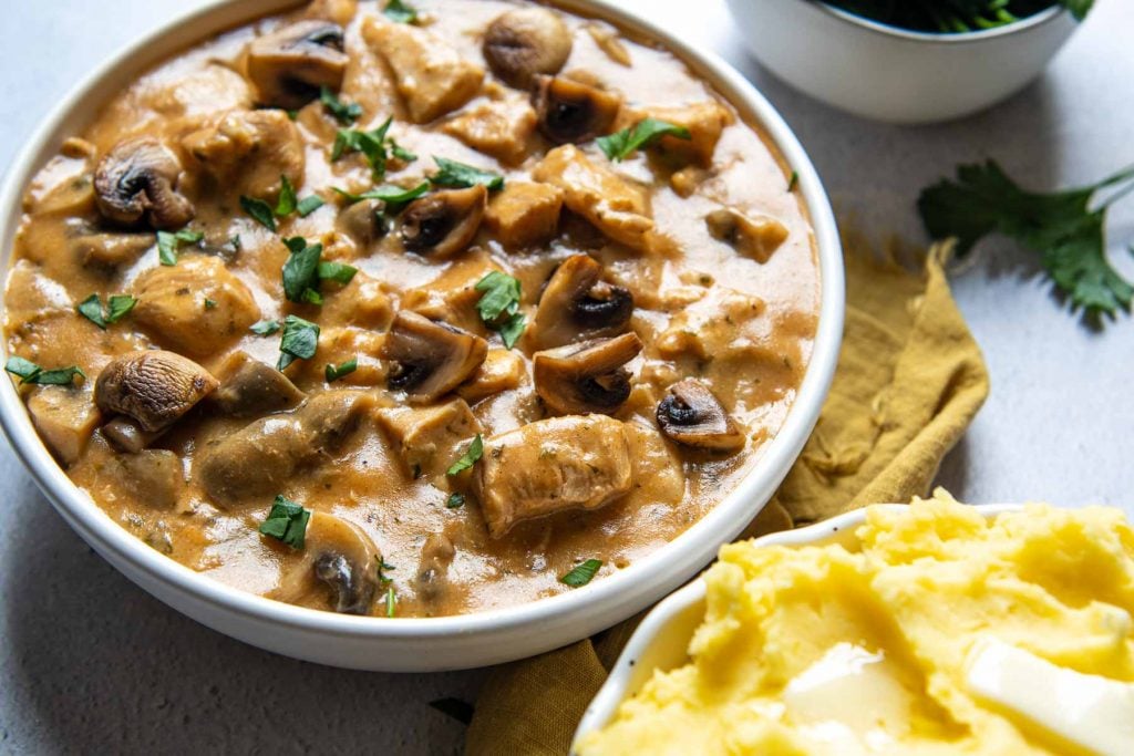 stroganoff in a white bowl with a gold napkin next to it