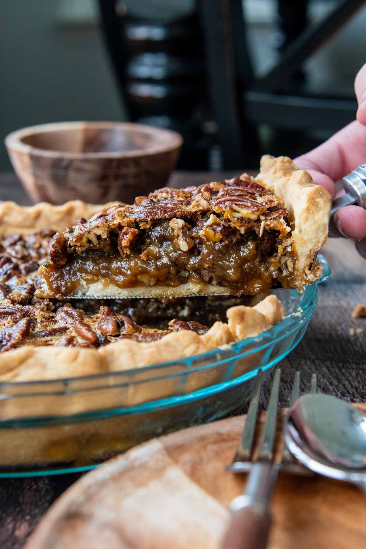 a piece of pecan pie being lifted out of a pie plate 