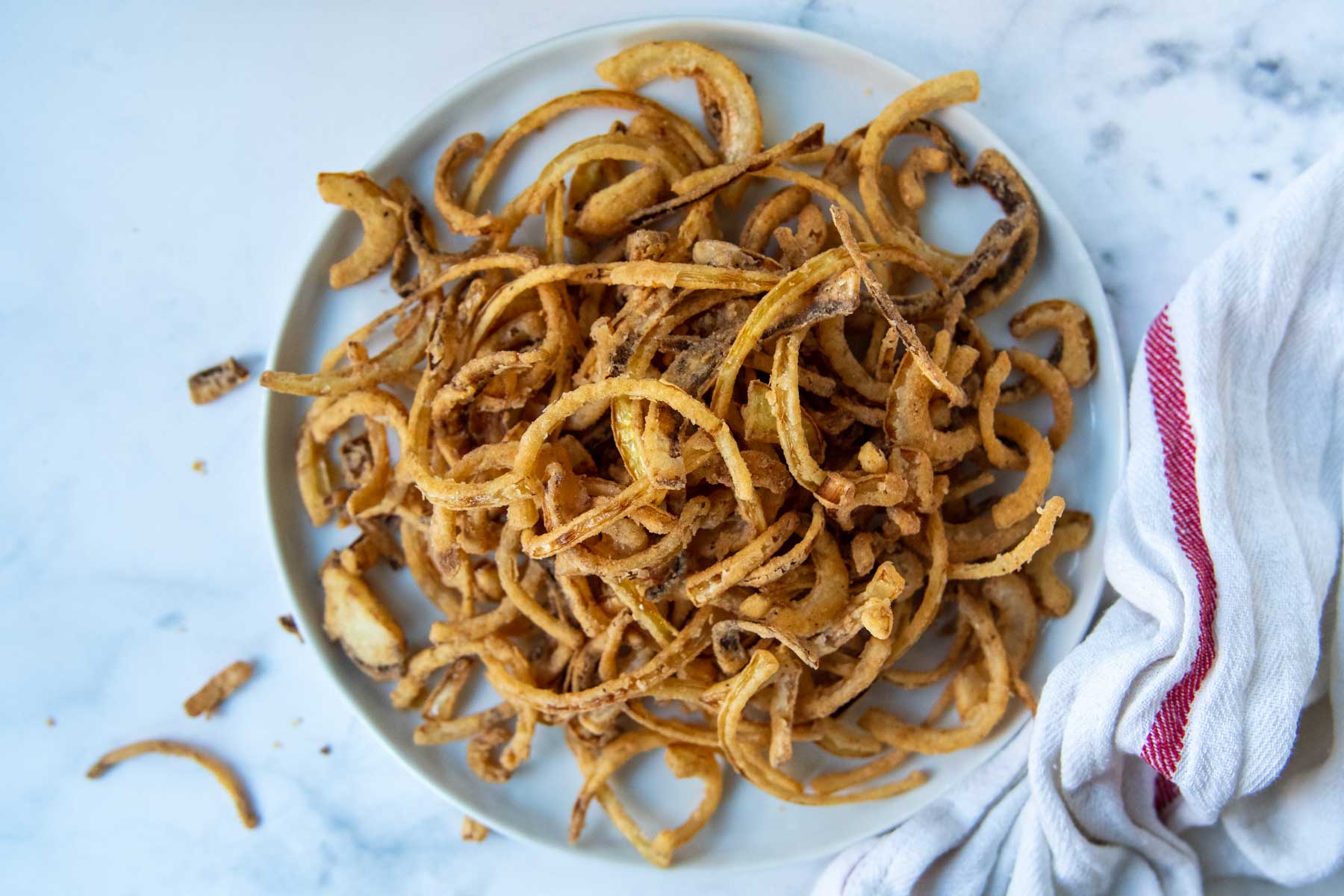 overhead shot of gluten-free french fried onions on a white plate
