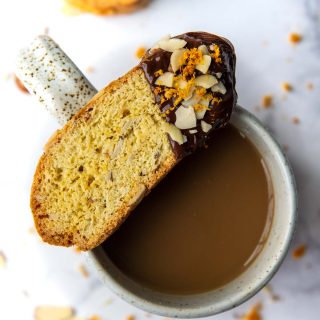 a gluten-free biscotti dipped in chocolate resting on top of a coffee cup