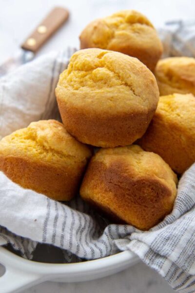 a basket of corn muffins lined with a white towel