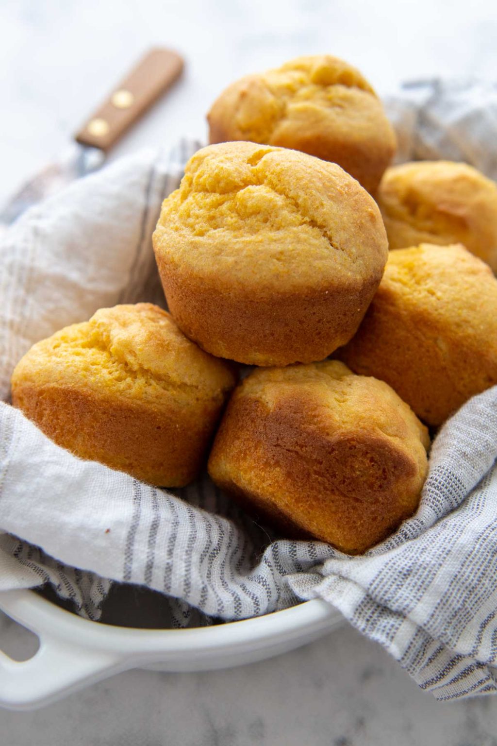a basket of corn muffins lined with a white towel