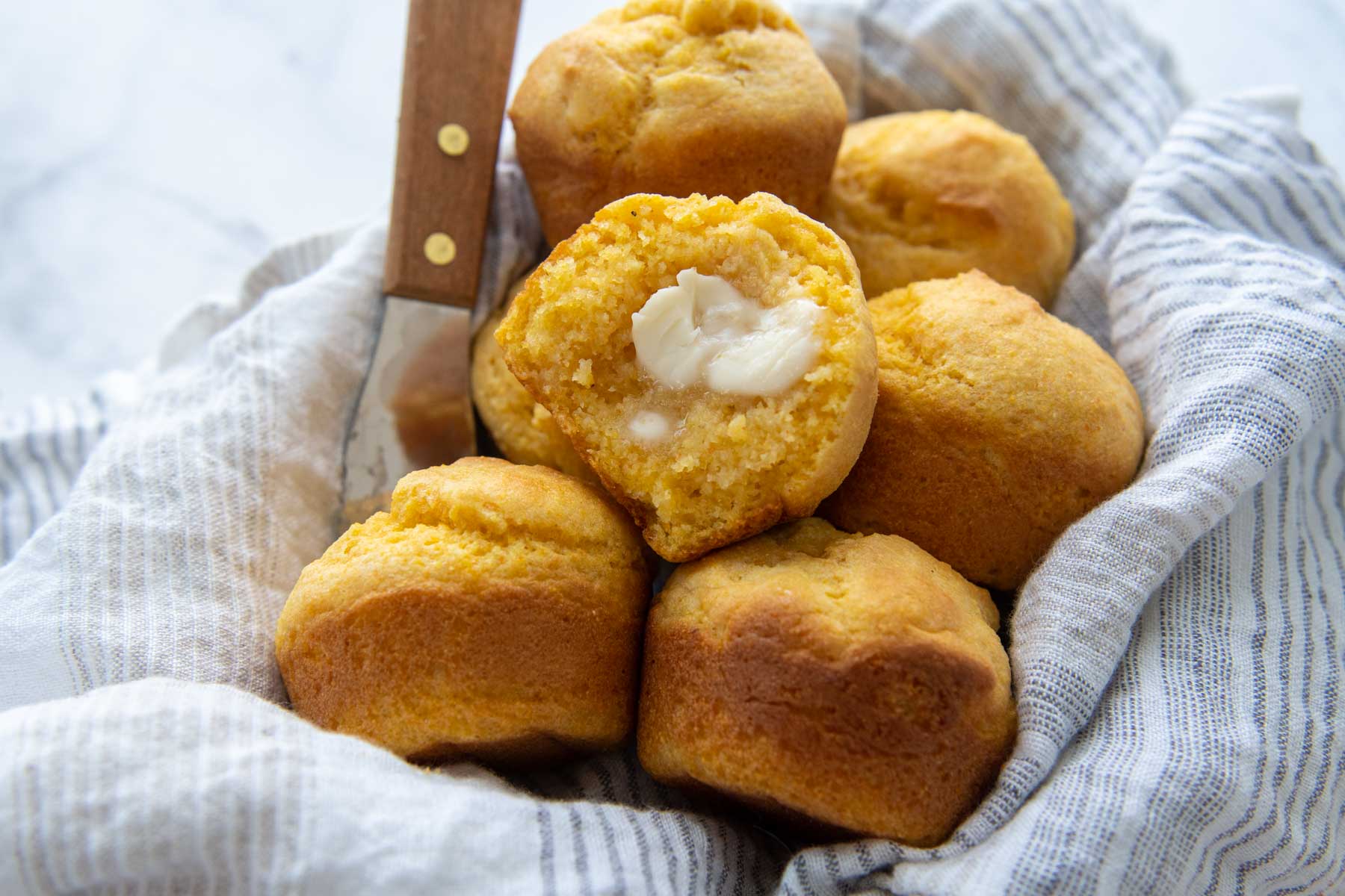 an open cornbread muffin with melting butter spread inside