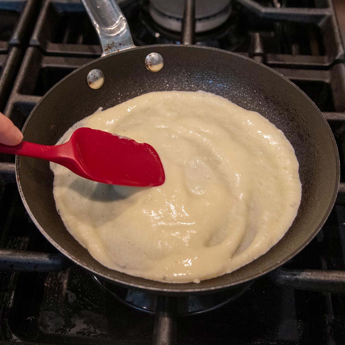crepe batter in a skillet being spread out.