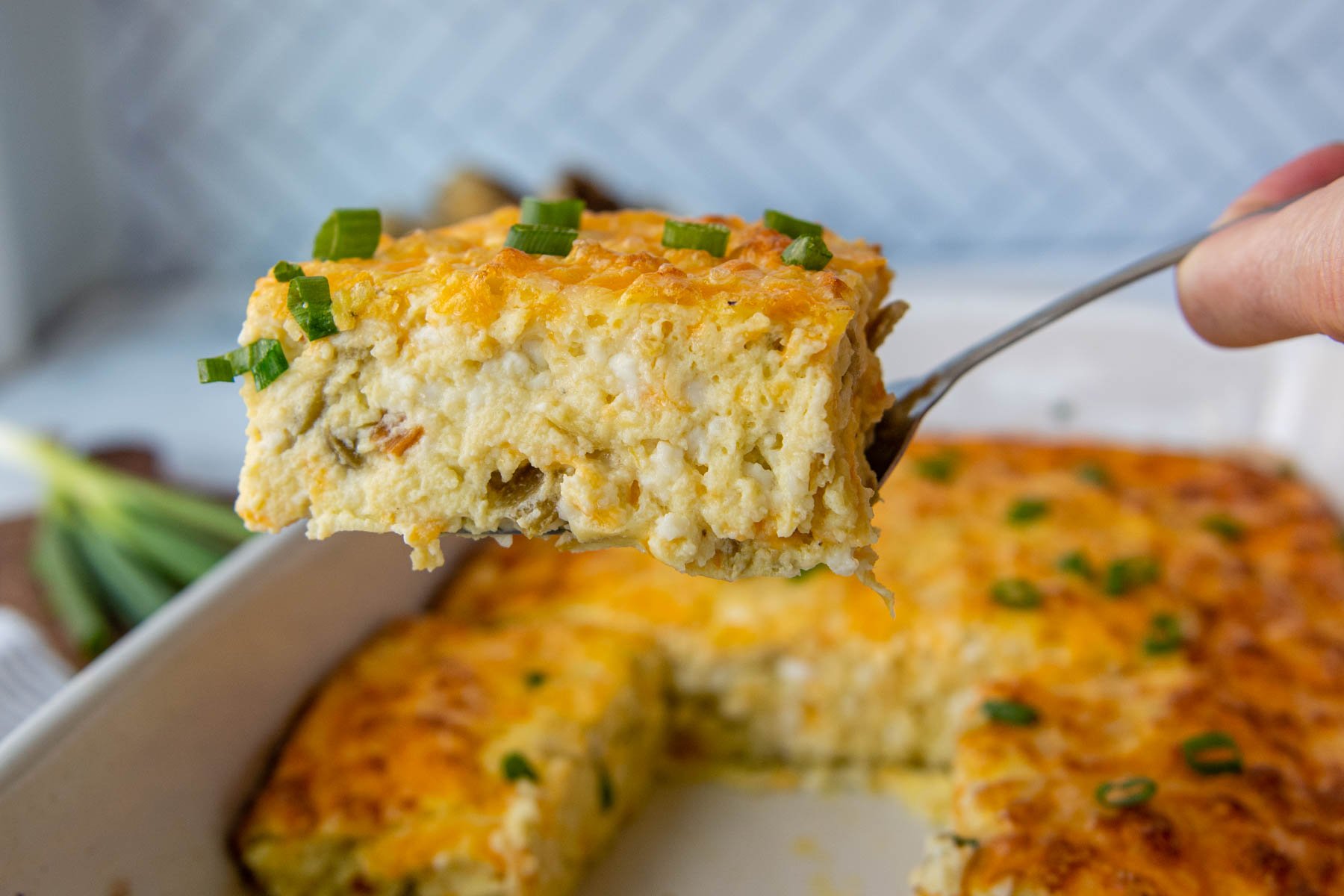a slice of green chile egg casserole being lifted up with a spatula