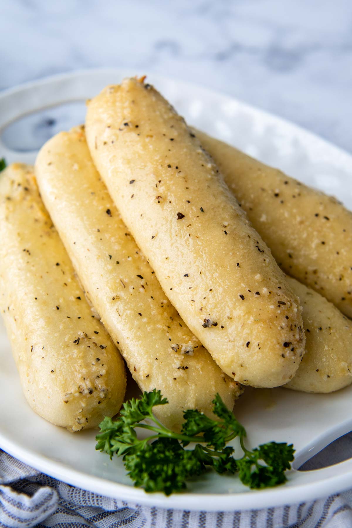 breadsticks stacked on a white plate with parsley