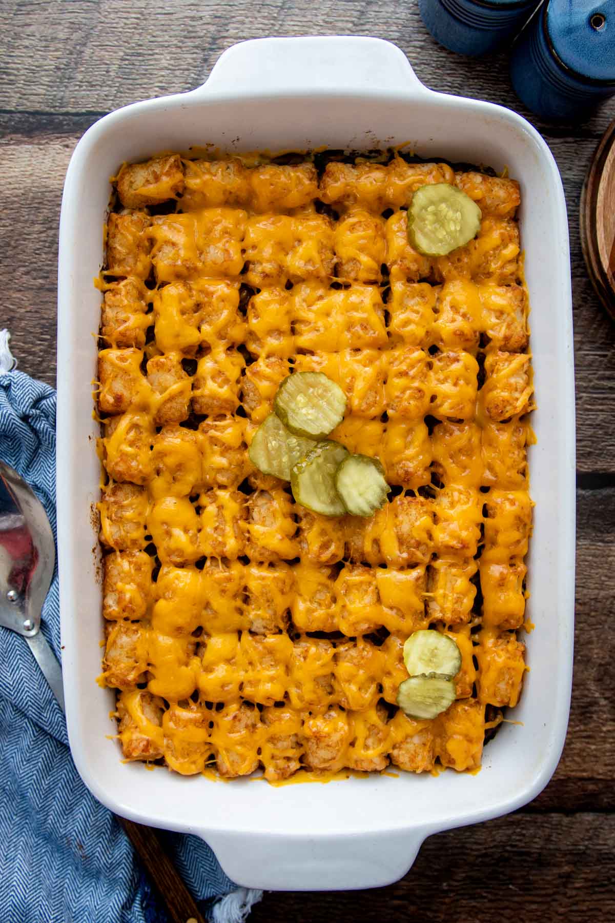 overhead shot of sloppy joe tater tot casserole with sliced pickles on top