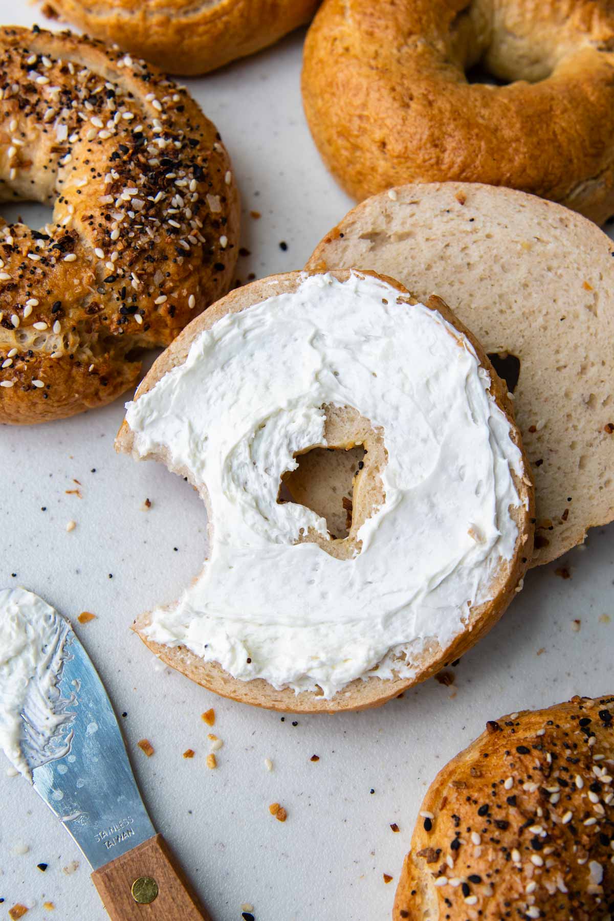 a bagel with cream cheese and a bite taken out of it.