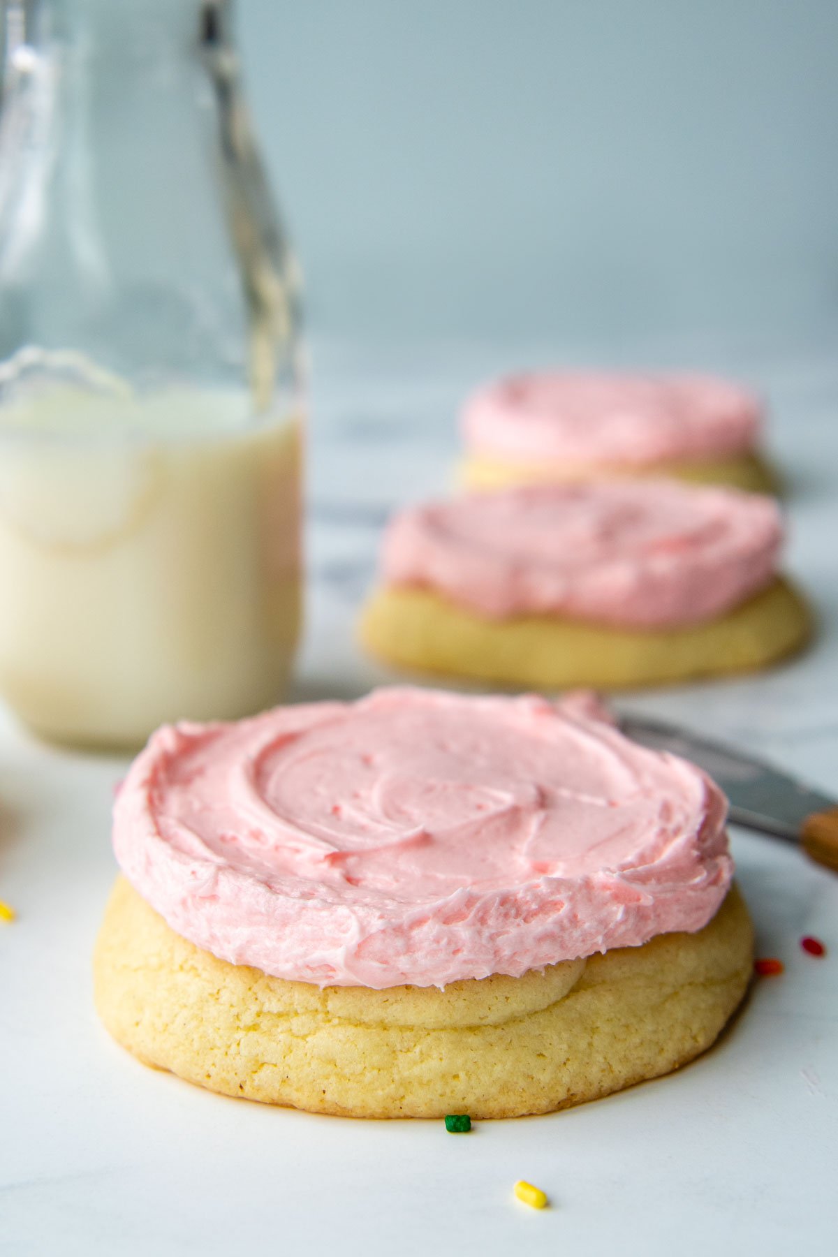 a close up straight on shot of a sugar cookie with pink frosting.