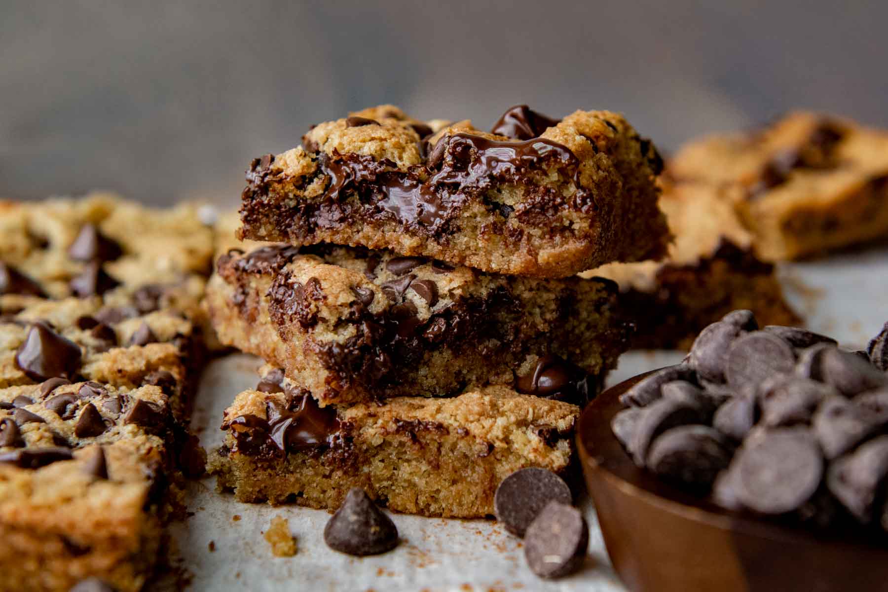 a stack of 3 blondies with a bowl of chocolate chips in the foreground.