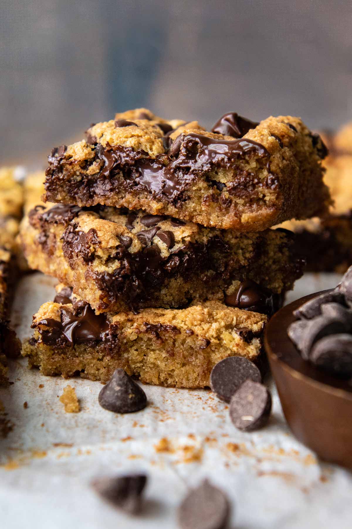 a stack of 3 blondies with melted chocolate and chocolate chips scattered around