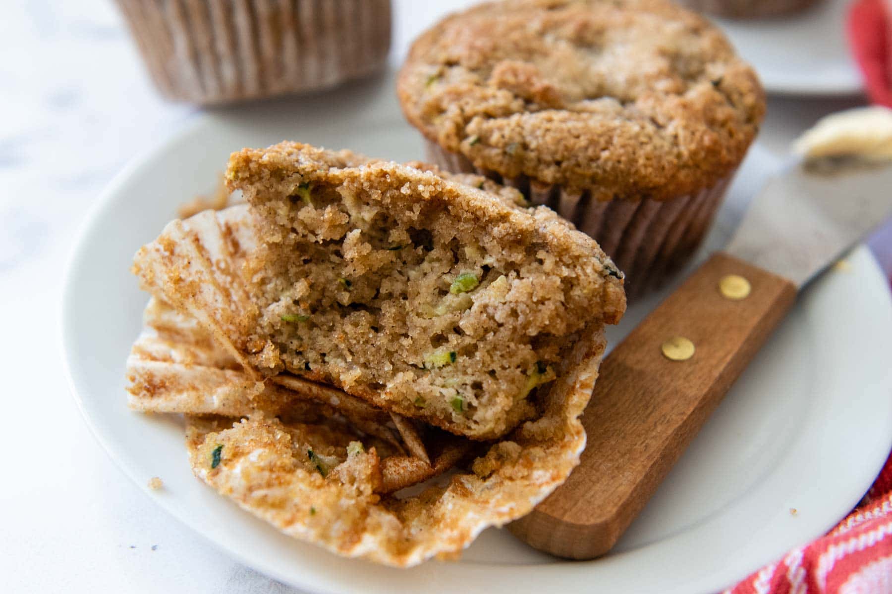 a zucchini muffin with a bite taken out on a white plate.