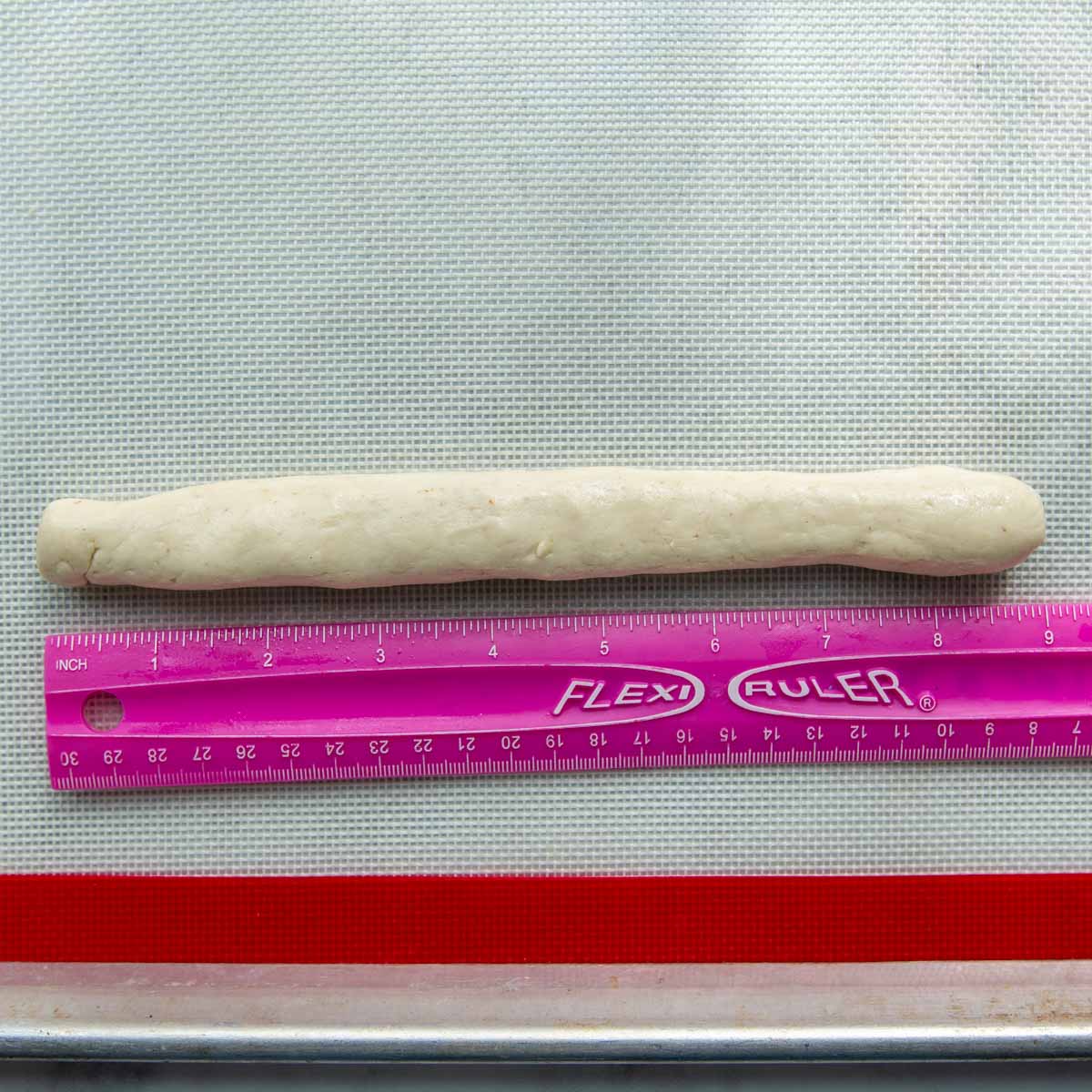 the dough rolled out into a rope with a ruler next to it.