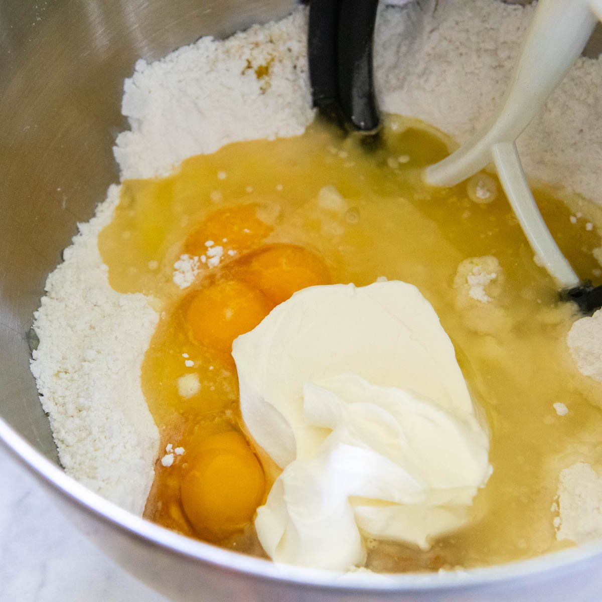 the dry ingredients being mixed with the sour cream, oil, eggs, and sour cream.