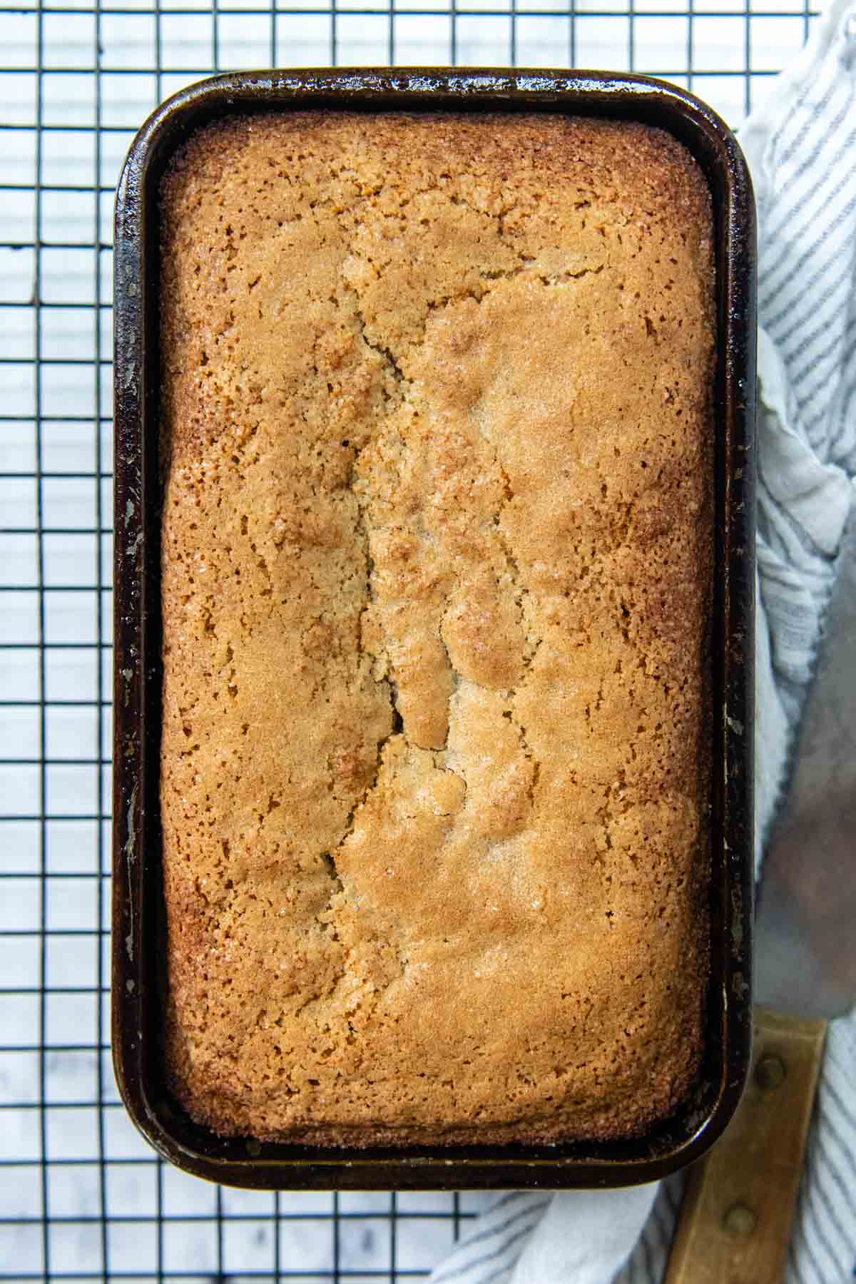 overhead shot of banana bread in a loaf pan on a wire rack.