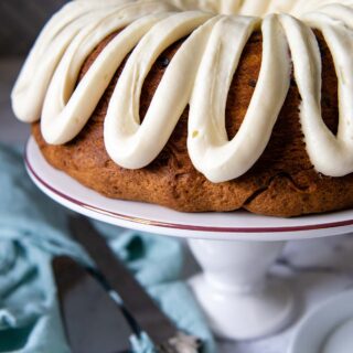 a chocolate chip bundt cake on white cake platter with a knife next to it.