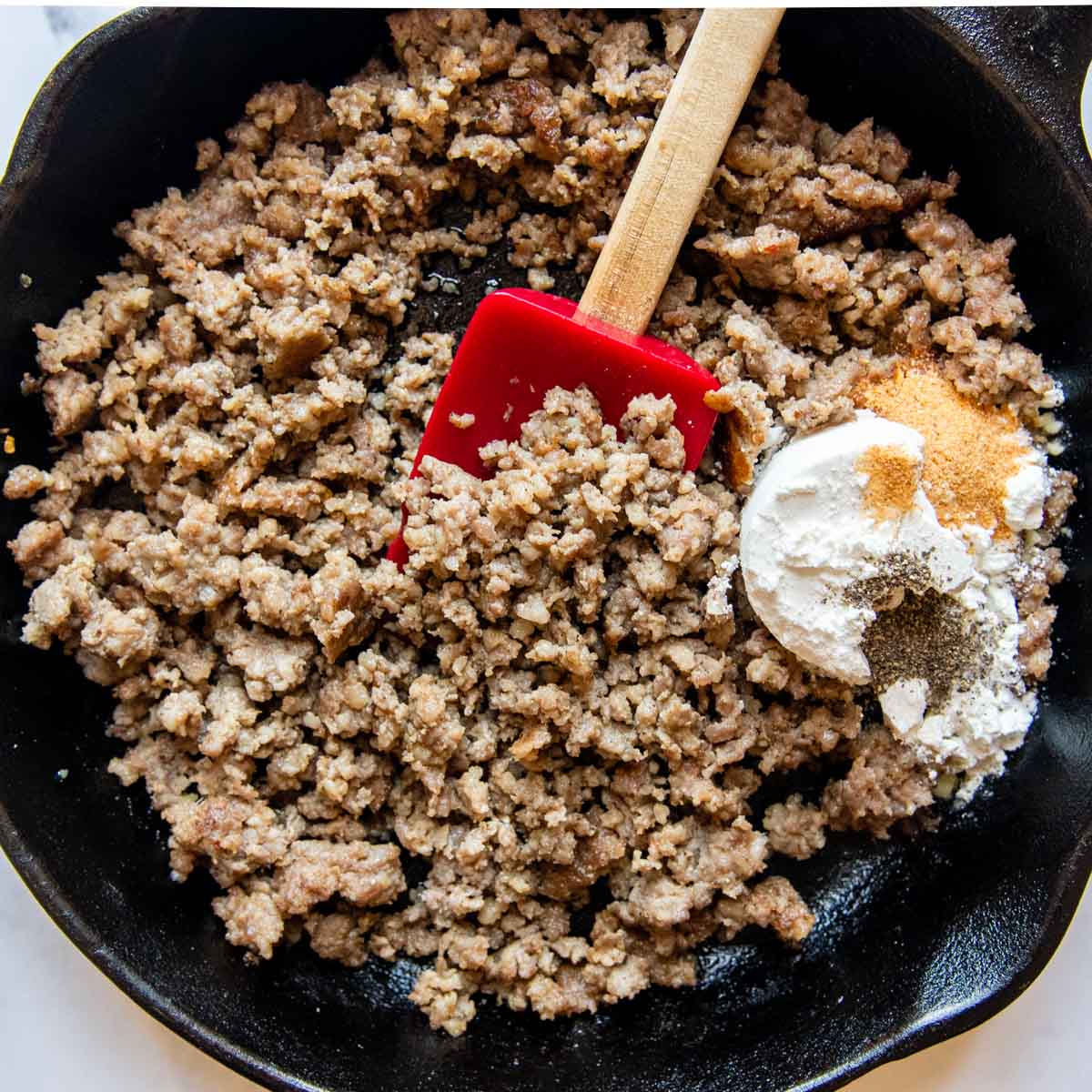 browned sausage in a skillet with flour and seasonings.