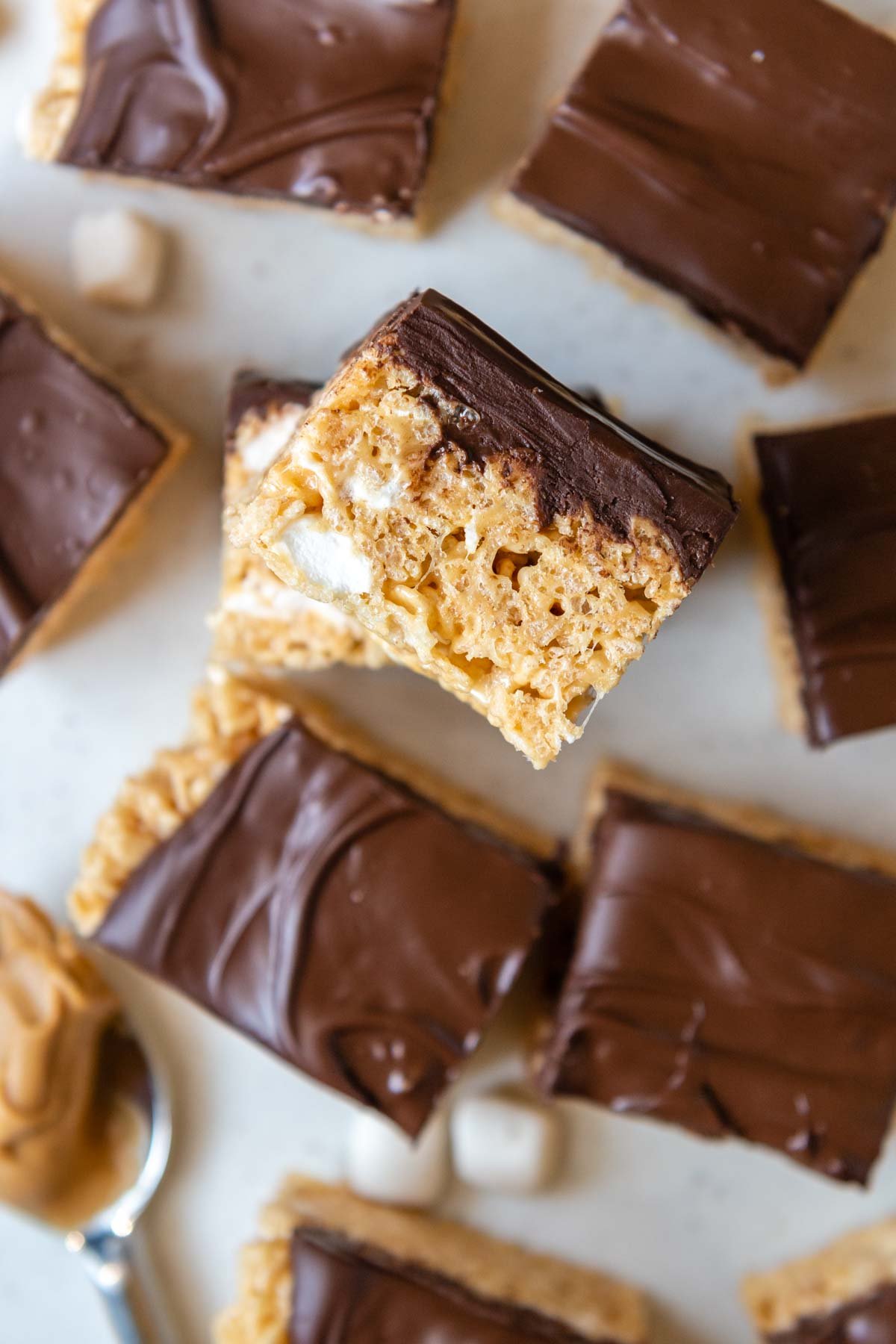 overhead shot of rice krispie treats with one face up and a spoonful of peanut butter next to it.