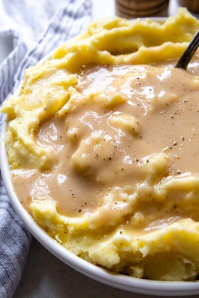 a bowl of mashed potatoes with gravy poured over it.