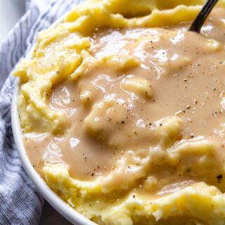 a bowl of mashed potatoes with gravy poured over it.