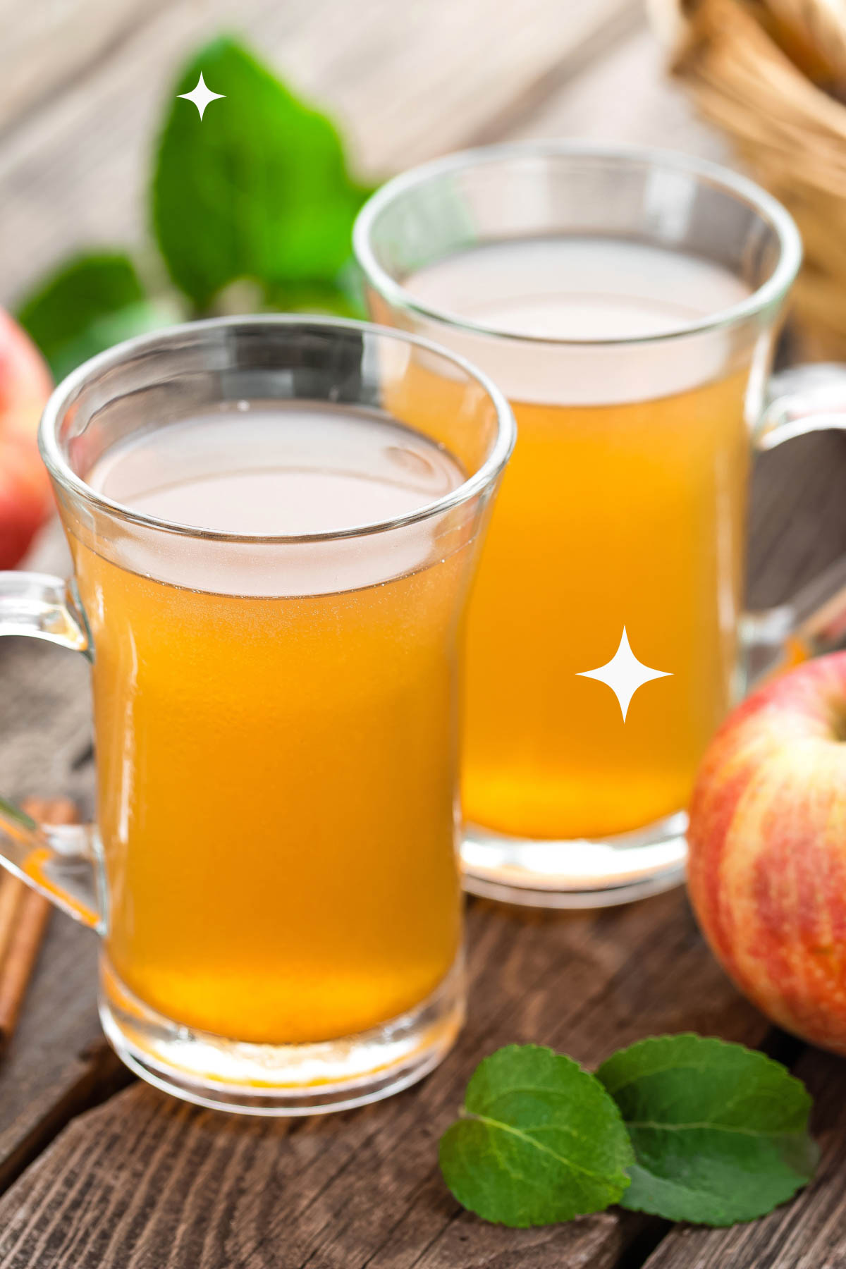 two glasses of apple cider with an apple.