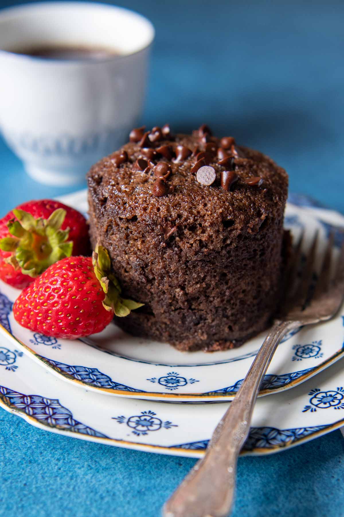 a mug cake taken out of the mug and placed on a plate with a fork nearby.