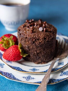 a mug cake taken out of the mug and placed on a plate with a fork nearby.