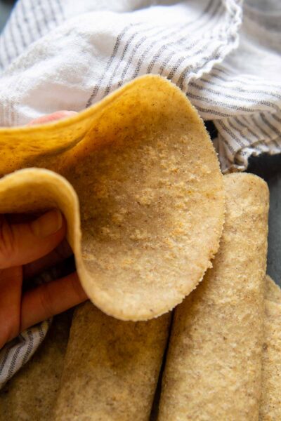 an almond flour tortilla being held up to show how flexible it is.
