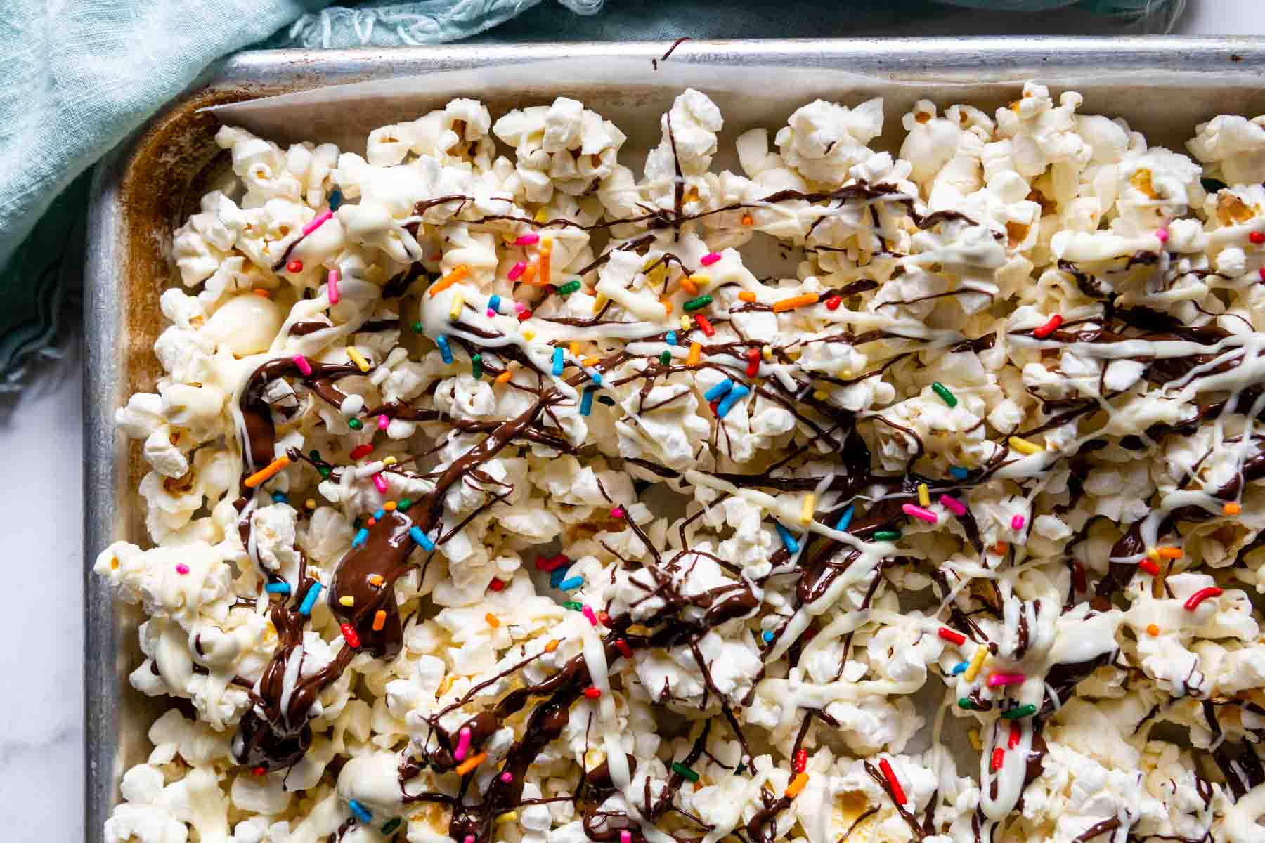 overhead shot of popcorn on baking sheet with chocolate and sprinkles.