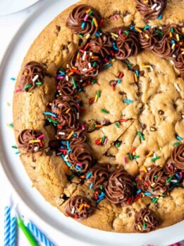 overhead shot of gluten free cookie cake with sprinkles and frosting on top.