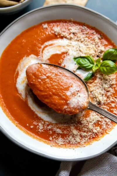 a spoon lifting out of a bowl of tomato soup.