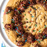 overhead shot of gluten free cookie cake with sprinkles and frosting on top.