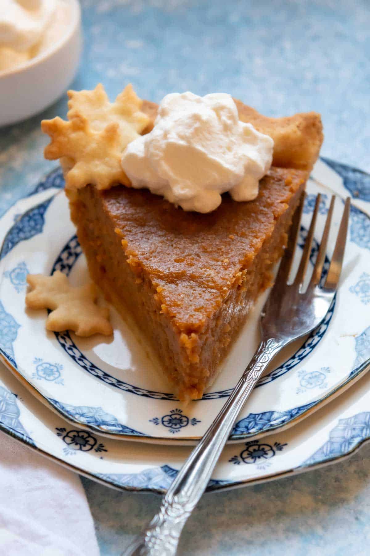 a slice of GF sweet potato pie on a blue and white plate with a fork nearby.